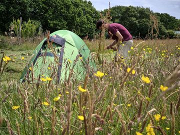 Backpacking tent on a grass pitch sharing shower, toilet, fire-pit and hot tub facilities