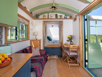 A cosy living space with kitchen and a two-seater sofa with king-size bed tucked into an alcove.
