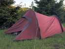 Tent in field. trees beyond.