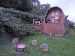 Pod at night with fire pit in front.
