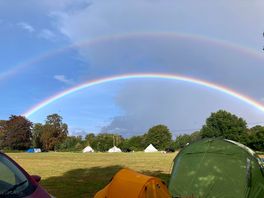 Double rainbow over bell tents and field wirh smaller tents in foreground