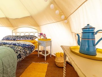 Interior of tent, with comfy double mattress, proper bedstead and cosy bedding.