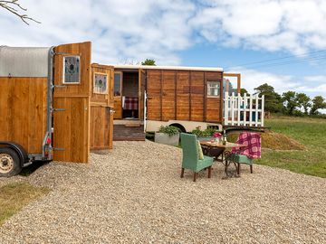 1 bedroom wooden horsebox lorry with private bathroom and outdoor seating.