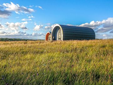 Pods set in a peaceful meadow with mountain and sea views