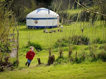 A child playing in the field by a yurt