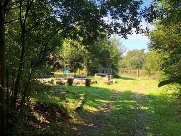 Log circle and mud kitchen looking towards the gate to the pitches