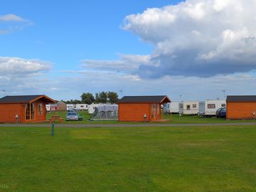 Glamping cabins with the tent area in the foreground and the touring area in the background