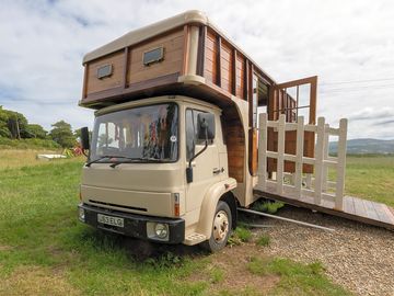 1 bedroom wooden horsebox lorry with private bathroom and outdoor seating.