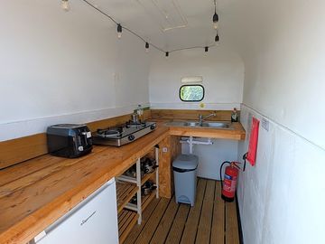 Covered kitchen trailer. shared fridge, 2 gas hobs and washing up sink.