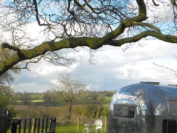 Airstream surrounded by trees and farmland