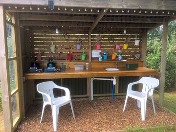 Camp kitchen with two gas rings and kettles, sink, solar lights