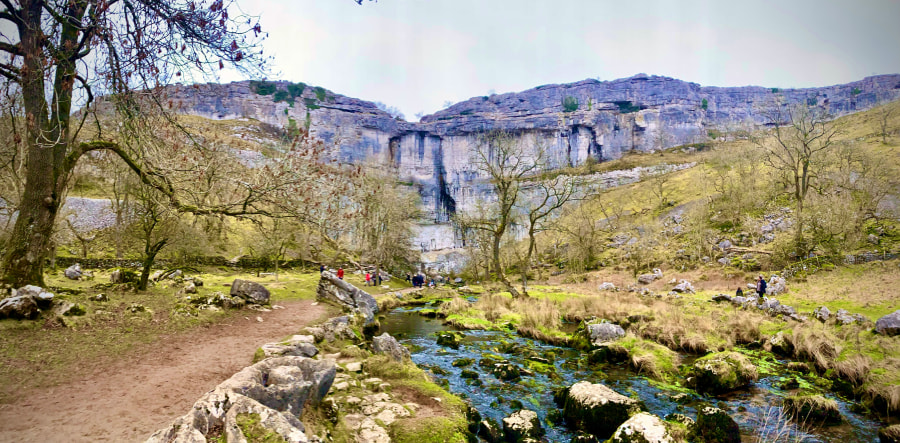 The riverside trail leading up to the limestone cliff at Malham Cove (Kitty Hutchinson/Unsplash)